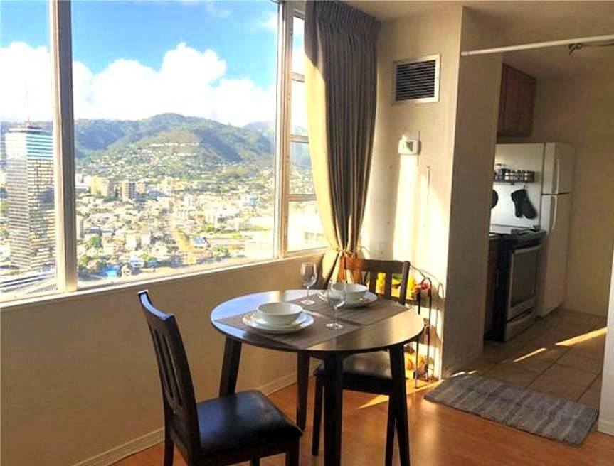 A table with two chairs is set for two in a room with a view of a city.